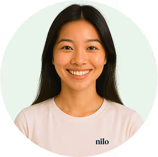 Smiling young woman with long dark hair wearing a light-colored shirt with the word 'nilo' on it.