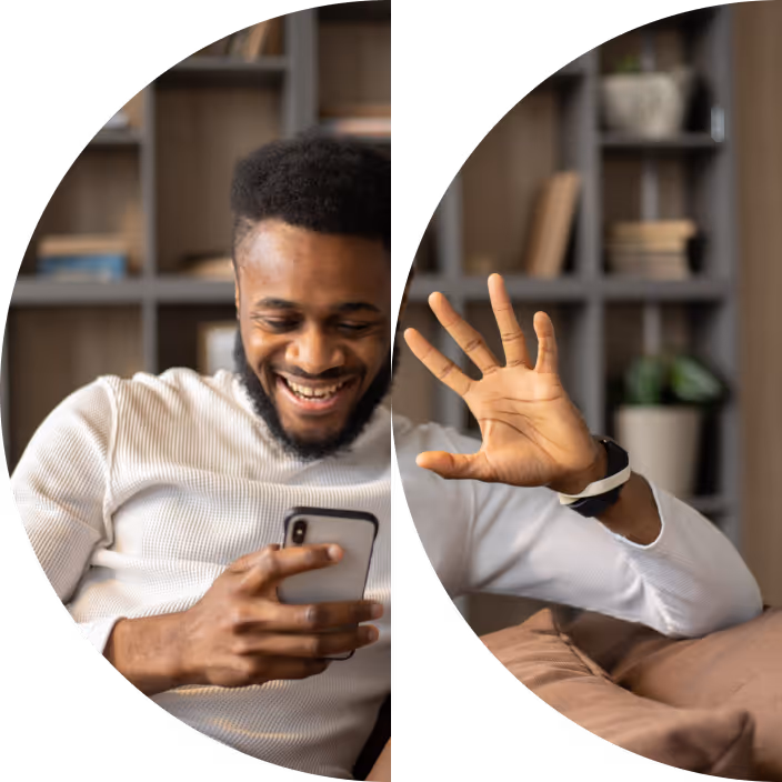 Um homem negro realizando uma videochamada no sofá de sua casa, acenando para a câmera de seu celular