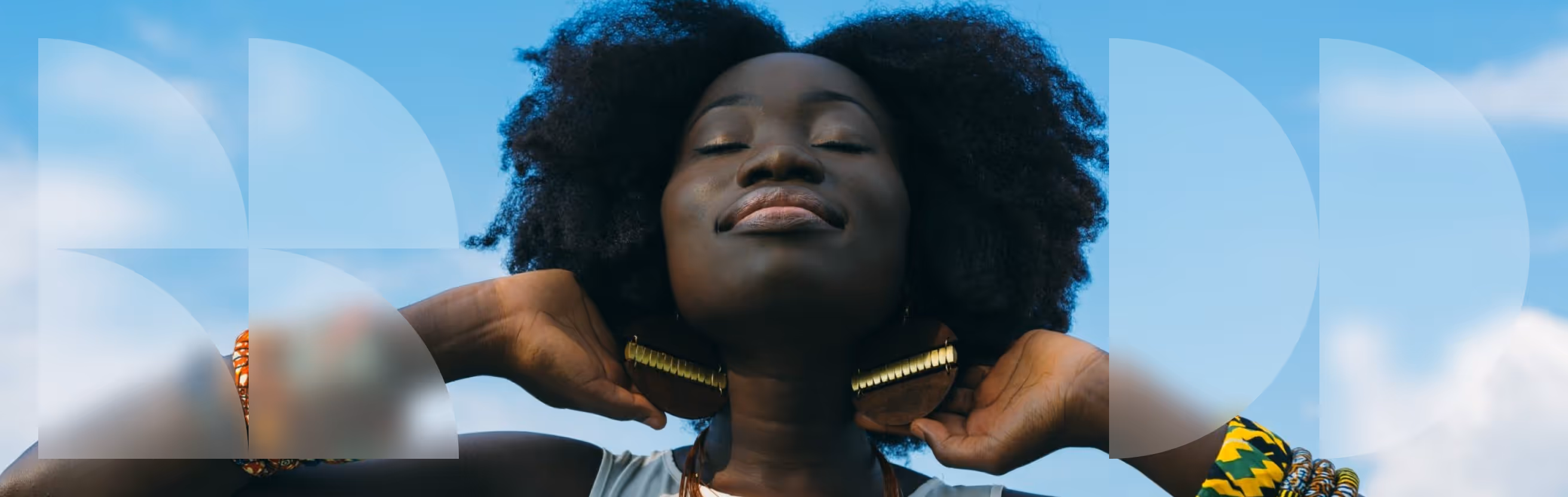 Mulher negra com as mãos atrás da cabeça, super relaxada, com um céu azul de poucas nuvens atrás