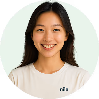 Smiling Asian woman with long dark hair wearing a white t-shirt against a light background.